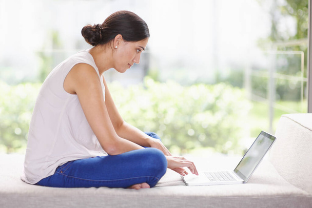 My wifi lets me browse anywhere I want. an attractive young woman using a laptop while relaxing at home - Foto, immagini