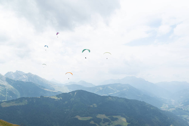 Um grupo de parapente voando sobre picos de montanha em um dia nublado em alpes franceses.  - Foto, Imagem