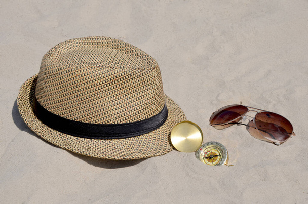 Strandmütze, Uhr und Sonnenbrille auf Sandhintergrund  - Foto, Bild