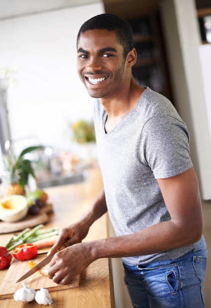 Hes a man of many talents. a handsome ethnic man preparing vegetables indoors - Zdjęcie, obraz