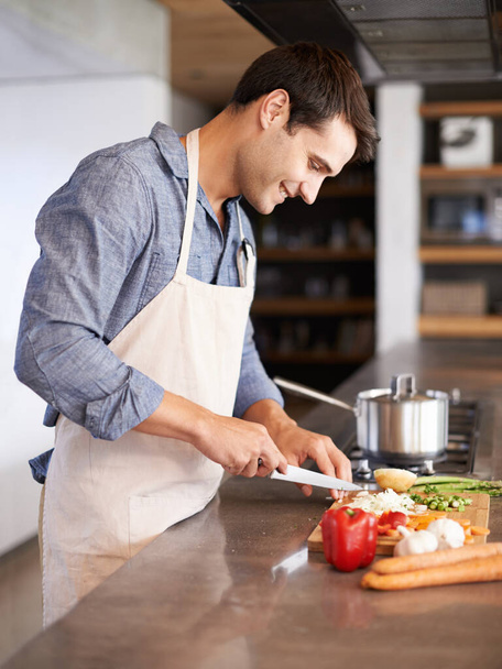 Справжні чоловіки готують. красивий молодий чоловік нарізає овочі на своїй кухні
 - Фото, зображення