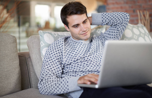 Робота над виснажливими проектами. чоловік розслабляється у своїй вітальні, використовуючи свій ноутбук
 - Фото, зображення