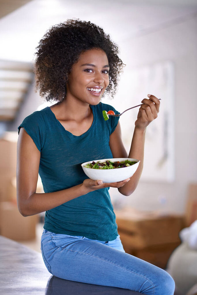 Shes loving her new diet. A beautiful young woman eating a bowl of salad at home - Photo, Image