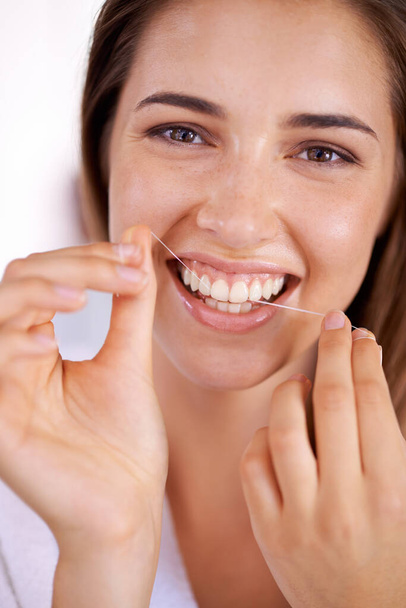 Zna znaczenie nici dentystycznej. Portret atrakcyjnej młodej kobiety z nitką dentystyczną i uśmiechem - Zdjęcie, obraz