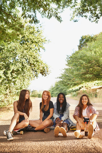 Lachen ist ein sofortiger Urlaub. Eine Gruppe von multirassischen Teenagern sitzt draußen und genießt die Gesellschaft der anderen - Foto, Bild