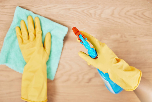 Cleaning spray, glove hands and wipe table, counter and wood surface for housekeeping service at home. Above of maid, janitor and cleaner dust cloth chore, furniture shine and chemical bottle product. - Photo, Image
