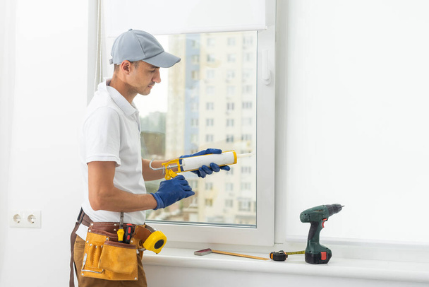 a repairman repairs, adjusts or installs metal-plastic windows in the apartment. glazing of balconies, loggias, verandas in house. production of double-glazed windows to individual sizes - Zdjęcie, obraz