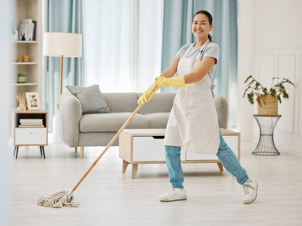 Asian cleaner woman mopping and cleaning dirt and dust in lounge or living room floor in house or home. Happy Japanese housekeeping help, hygiene maid or employee tidy and spring cleaning apartment. - Photo, Image