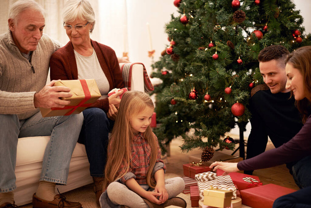 Dzieląc specjalne chwile świąteczne. wielopokoleniowa rodzina wymieniająca się prezentami na Boże Narodzenie - Zdjęcie, obraz