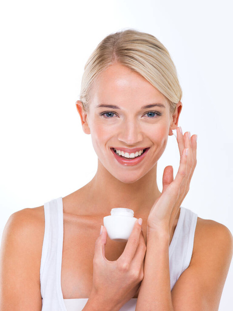My favourite moisturiser. A beautiful young woman applying moisturiser to her face - Fotografie, Obrázek