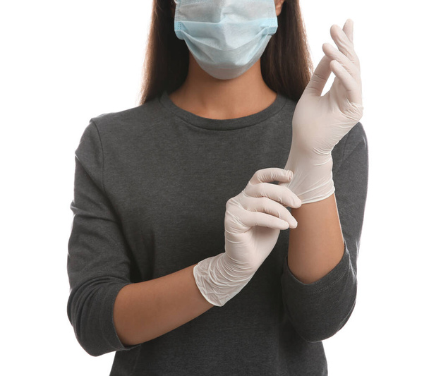 Woman in protective face mask putting on medical gloves against white background, closeup - Fotoğraf, Görsel
