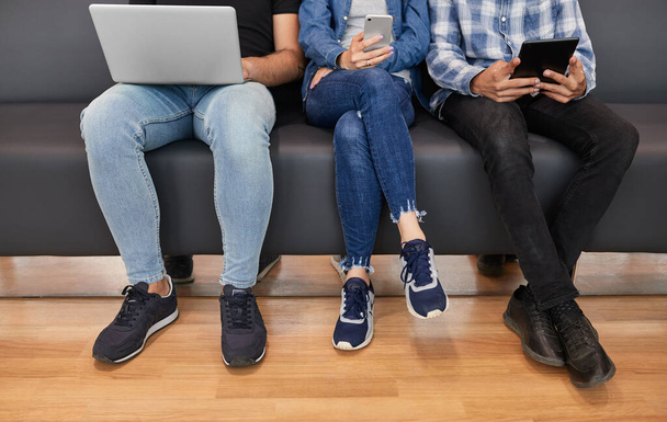Unrecognizable men and woman in casual clothes sitting on sofa together and browsing gadgets in waiting room - Photo, image