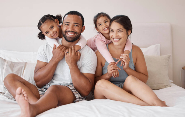 Young couple smile on bed, with children in their home or apartment. Happy multicultural family, in bedroom with toddler kids while on weekend vacation or holiday together for portrait. - Foto, Imagem