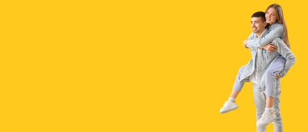 Κομψό ευτυχισμένο ζευγάρι σε τζιν ρούχα σε κίτρινο φόντο με χώρο για κείμενο - Φωτογραφία, εικόνα