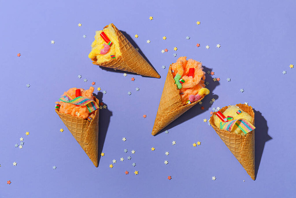 Wafer cones with delicious cotton candy and sprinkles on color background - 写真・画像