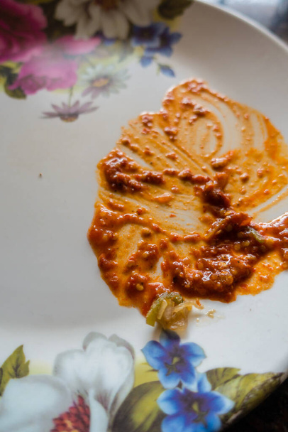 Ein nach dem Imbiss leerer weißer Teller mit übrig gebliebener roter Soße. Indien - Foto, Bild