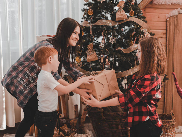Mère et fils offrent un cadeau de Noël à leur fille. Présentation des cadeaux de Noël. - Photo, image