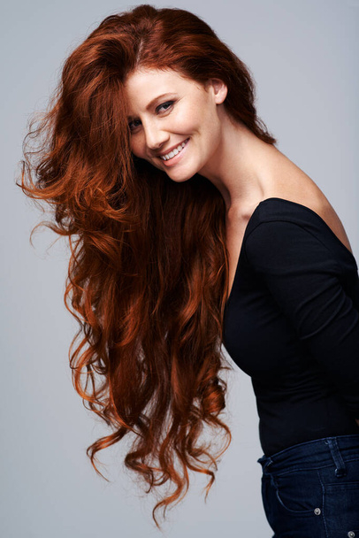 Life isnt perfect but at least my hair is. Studio shot of a young woman with beautiful red hair posing against a gray background - Фото, изображение