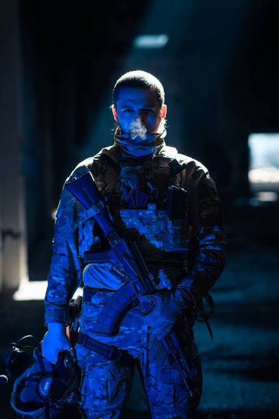 Army soldier in Combat Uniforms with an assault rifle and combat helmet night mission dark background. Blue and purple gel light effect. High quality photo - Φωτογραφία, εικόνα