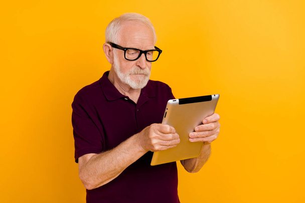 Photo of senior man look read browse tablet manager agent eyewear isolated over yellow color background. - Фото, изображение
