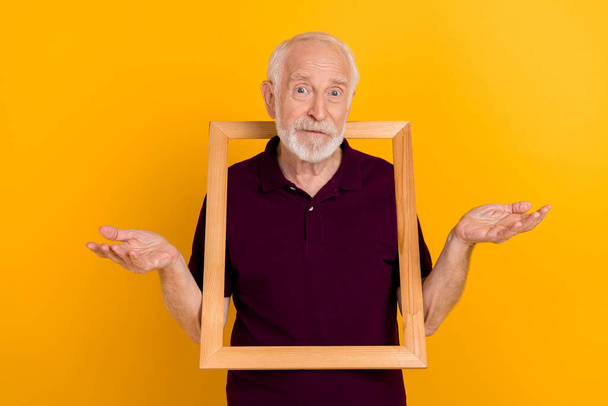 Photo of mature man puzzled make picture album shrug shoulders isolated over yellow color background. - Fotoğraf, Görsel