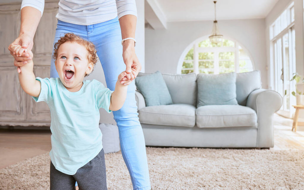 Mother helping baby walk his first steps in living room for child development, growth and physical progress with lens flare. Young excited kid learning, walking with love and support from mom at home. - Photo, image