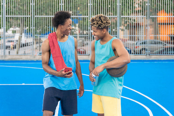 Afro american basketball player friends finishing practice on the court talking and laughing. - Foto, imagen