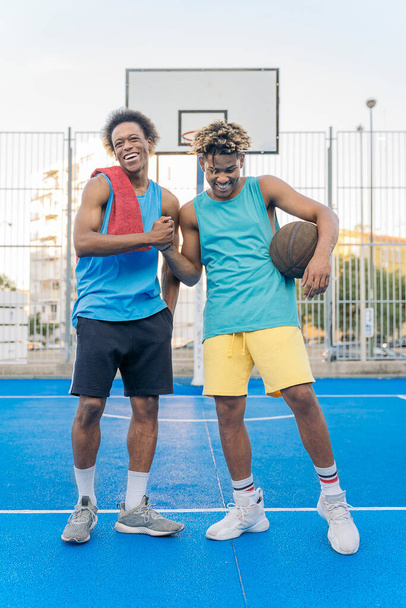 Coole afrikanisch-amerikanische Männer, die im Basketballfeld lächelnd in die Kamera schauen. - Foto, Bild
