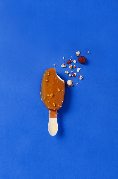 Νόστιμο παγωτό σοκολάτα με ξηρούς καρπούς σε μπλε φόντο. - Φωτογραφία, εικόνα