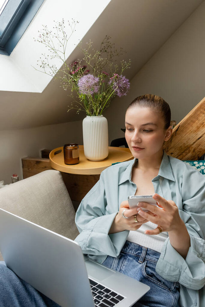 Young freelancer using devices and sitting on couch at home  - Photo, Image