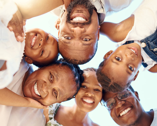 Happy black family in a huddle, face smile with mother, father, grandmother and their cute children from below. Group of people with support, trust and love together outdoor with blue sky background. - Foto, immagini