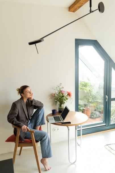 Freelancer in jacket sitting near gadgets and cup at home  - 写真・画像