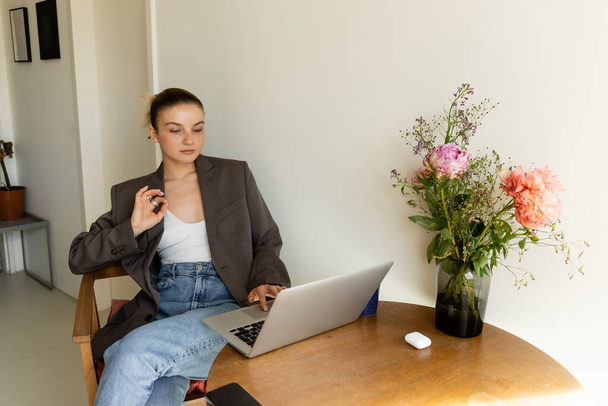 Woman in jacket showing ok gesture while using laptop at home  - Fotó, kép