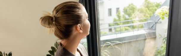 Jeune femme regardant la porte du balcon à la maison, bannière  - Photo, image