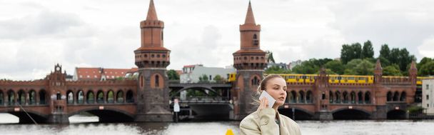 Woman talking on mobile phone with Oberbaum bridge at background in Berlin, banner  - Foto, imagen