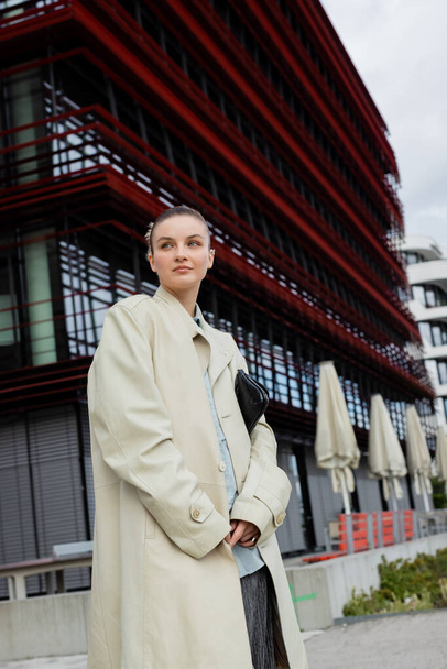 Молодая женщина в пальто смотрит на городскую улицу в Берлине  - Фото, изображение