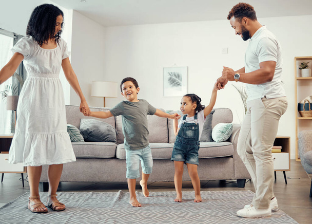 Happy family, dancing and having fun while sharing love, energy and bond while holding hands in the living room at home. Man, woman and sibling kids playing and laughing enjoying active time together. - Valokuva, kuva