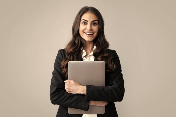 Beautiful smiling business woman over grey background using laptop computer - Photo, Image
