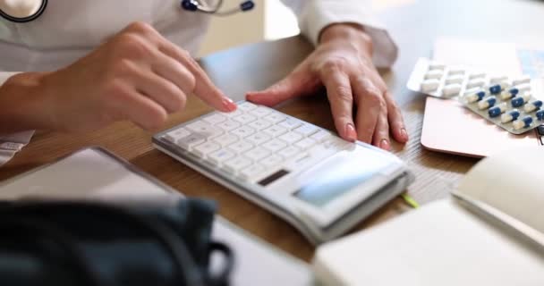 Ärzte mit Stethoskop berechnen Kosten und Einnahmen für die Bezahlung medizinischer Leistungen. Arzt mit Taschenrechner im Krankenhaus - Filmmaterial, Video