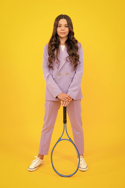 Tini teniszező lány tartja tenisz ütő felett elszigetelt sárga háttér. Sport gyerekeknek. Képzés fiatal gyereknek. A gyermek teniszezni tanul - Fotó, kép