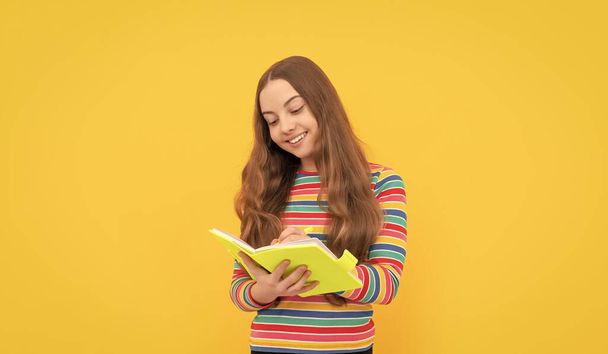 Happy girl dziecko zapisać w copybook żółty tle, pisanie. - Zdjęcie, obraz
