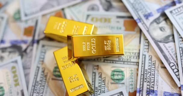Zlaté cihly na pozadí amerických dolarů bankovek. Budoucí obchodování se zlatem a on-line obchodování s aktivy nebo nákup zlatých prutů pro investice - Záběry, video