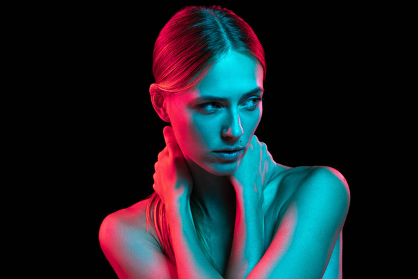 Pride and freedom. Young adorable woman with naked shoulders and well-kept skin in red neon light on dark background. Art, creativity, fashion, style and ad concept - 写真・画像