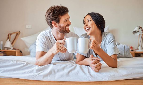 Χαρούμενο πρωινό, καφές και ζευγάρι χαμόγελο στο κρεβάτι αίσθημα χαλάρωσης, την αγάπη και την ευτυχία σε ένα σπίτι υπνοδωμάτιο. Χαμογελαστός φίλος και φίλη μαζί σε ένα σπίτι γελώντας και περνώντας ποιοτικό χρόνο πίνοντας τσάι. - Φωτογραφία, εικόνα