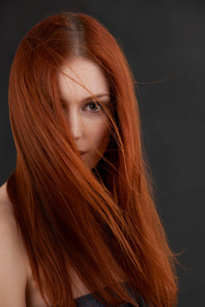 Ő egy szépség. Portré egy gyönyörű fiatal vörös hajú nő fekete háttér - Fotó, kép
