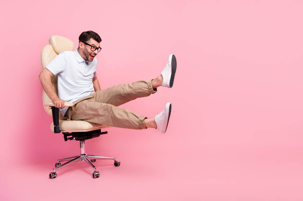 Full length photo of excited guy look copyspace fast ride chair game isolated on pastel color background. - Фото, изображение