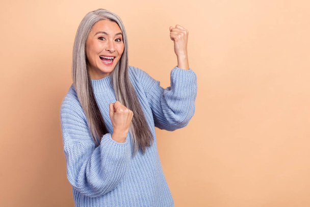 Photo of cheerful funny laughing girl raise fists in victory triumph win in lottery prize isolated on beige color background. - Fotografie, Obrázek