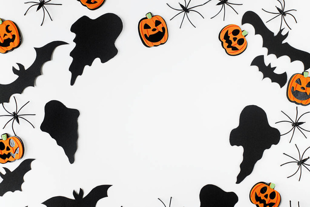 Halloween tasainen makasi. Mustat aaveet, hämähäkit, lepakot ja oranssi kurpitsat koristeet valkoisella taustalla. Hauskaa Halloweenia! Korttimalli, jossa on tilaa tekstille. Tyylikäs rungon koostumus - Valokuva, kuva