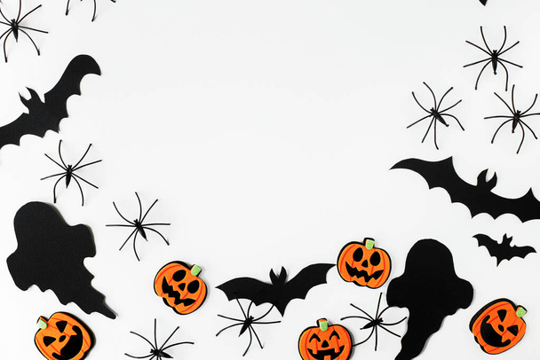 Halloween. Musta aaveita, hämähäkkejä, lepakoita ja oranssi kurpitsat koristeet valkoisella taustalla tasainen lay. Hauskaa Halloweenia! Korttimalli, jossa on tilaa tekstille. Tyylikäs rungon koostumus - Valokuva, kuva