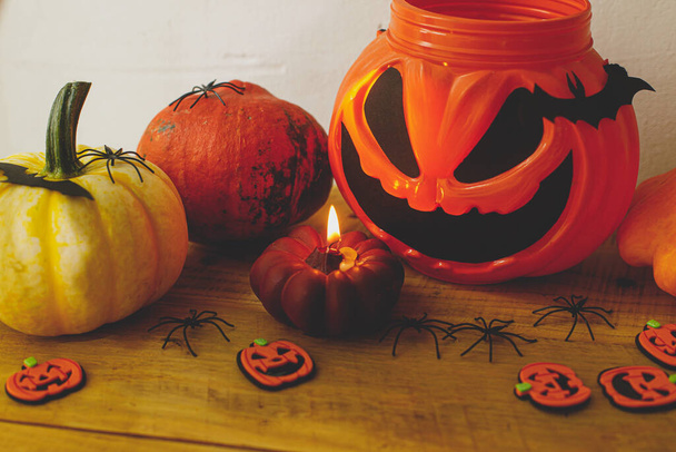 Šťastný Halloween! Jack z lucerny kbelík cukroví, dýně, černé pavouky, netopýři a duchové dekorace na venkovském pozadí ve večerní místnosti. Strašidelný Halloween zátiší. Trick or treat! - Fotografie, Obrázek